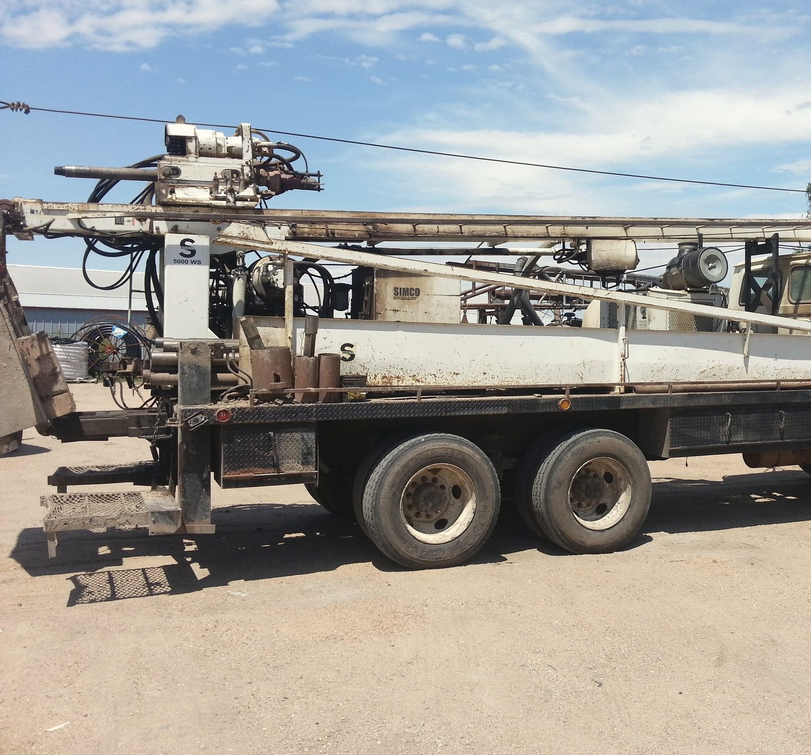 The deck of a truck-mounted water well drilling rig parked on a gravel yard